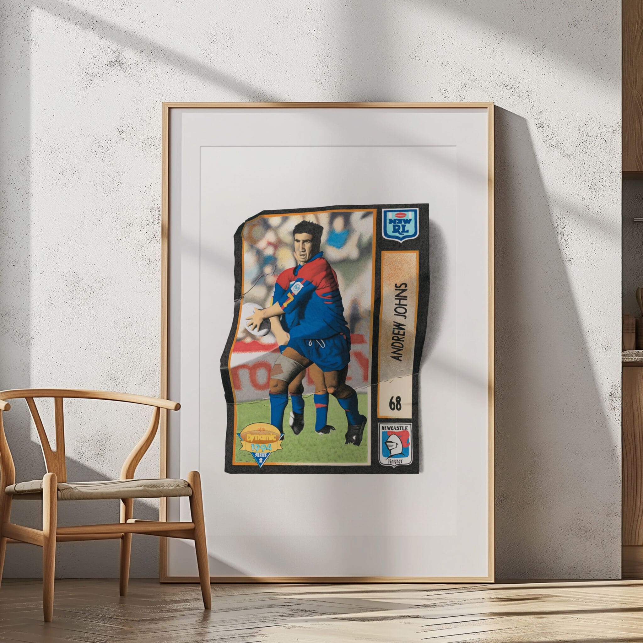 Andrew Johns Newcastle Knights footy card art print in a timber frame against a sunlit white wall.