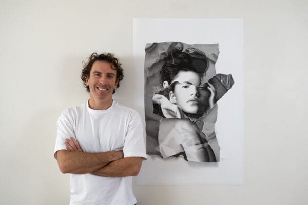 Dean Spinks, Australian artist, standing beside his photorealistic drawing "The Forbidden Enigma".